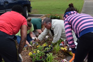 Curtis Hawkins and the girls work on digging up flowers and preserving the root for replanting.